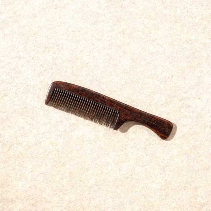 A well-used comb, photographed on bone-coloured paper.