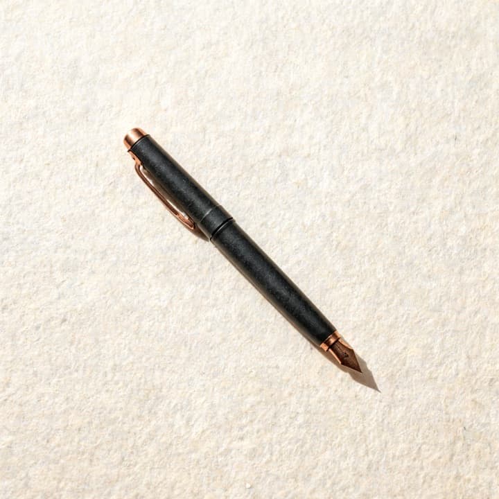 A well-used fountain pen, photographed on bone-coloured paper.